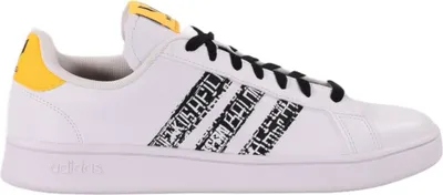 A side view of a white Adidas sneaker with black laces and yellow accents.