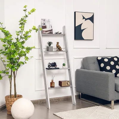 A ladder shelf with decorative items and a plant next to a sofa in a living room.