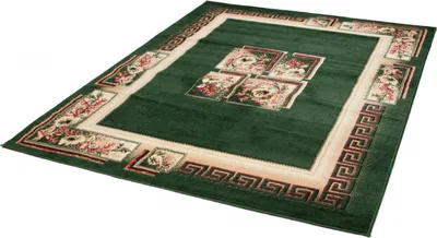 A green rug with a cream border and floral patterns is shown from a diagonal angle against a white background.