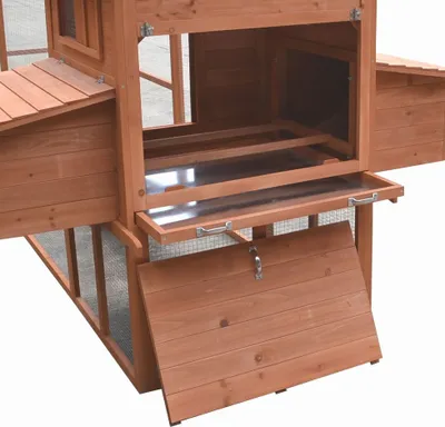 A close-up view of a wooden chicken coop with its doors and trays open.
