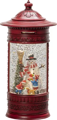 A festive Christmas snow globe in the shape of a red mailbox, featuring a snowman, children, a dog, and a Christmas tree inside.