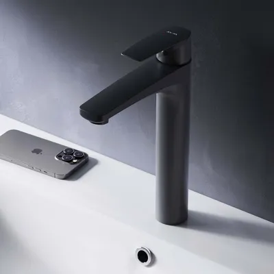 A modern black faucet is shown on a white sink next to a smartphone.