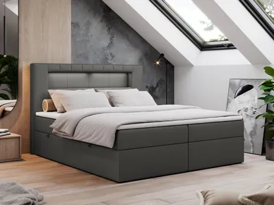 A modern bedroom with a large bed under a slanted ceiling with skylights.