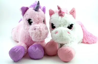 Two plush unicorn toys lying down on a white background.