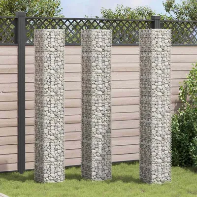 Three gabion planters are arranged in a garden setting against a wooden fence.