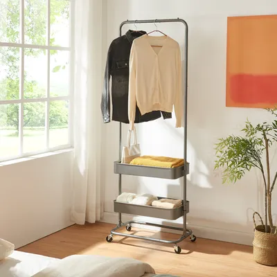 A garment rack with clothes and folded items, placed near a window with natural light.