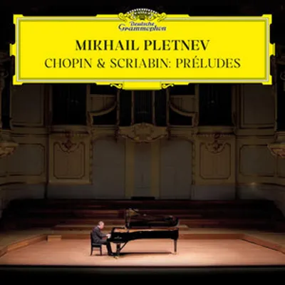 A pianist performs on a grand piano on a stage in a concert hall.