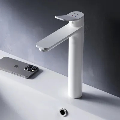 A white faucet is shown on a white sink next to a smartphone.