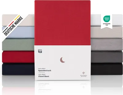 A stack of folded fitted sheets in various colors, with a red one prominently displayed in the center, showcasing product packaging and certifications.
