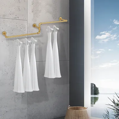A gold pipe rack with white garments hanging on it, set against a concrete wall with a large window showing a lake and sky.