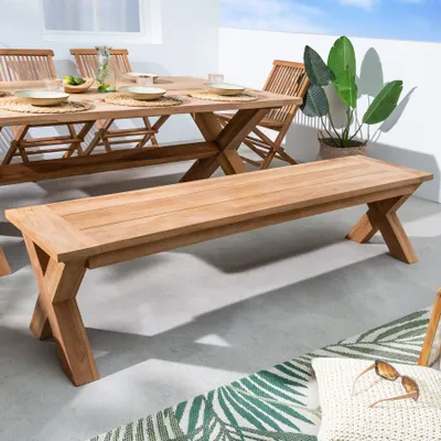 An outdoor patio scene with a teak dining set and a bench.