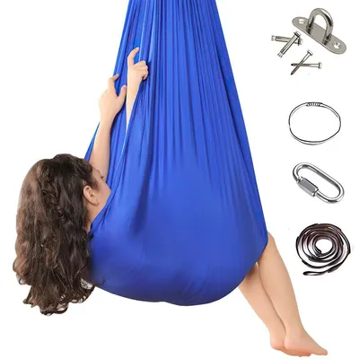A person is inside a blue aerial yoga hammock, with various accessories for hanging the hammock laid out to the right.