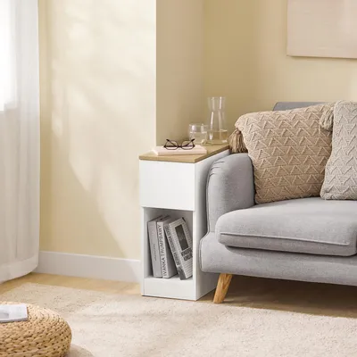 A narrow side table is placed next to a sofa, with books and a glass of water on top.