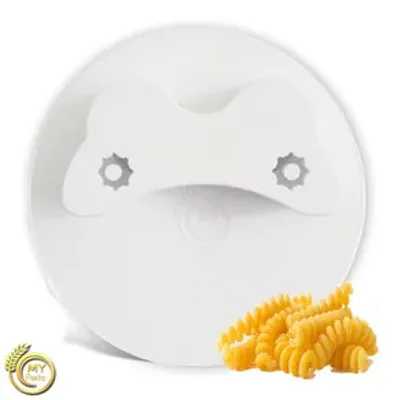 A white pasta maker attachment with a few fusilli pasta shapes in front of it.