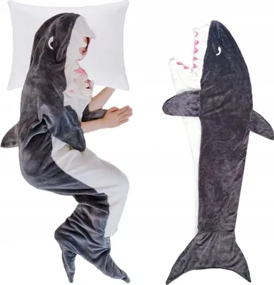 A person sleeping in a shark-shaped blanket next to a pillow, and the blanket itself laid out flat.