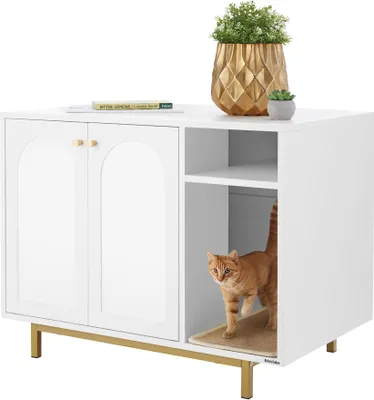 A white cat cabinet with gold legs and gold handles, featuring a side entrance where an orange cat is standing. Decorative plants and a book are on top.