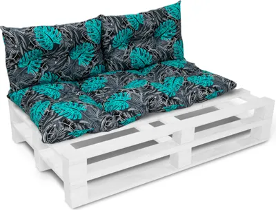 A white wooden pallet with teal and black patterned cushions on top, forming a sofa.