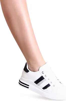 A close-up shot of a person's lower leg and foot wearing a white sneaker.