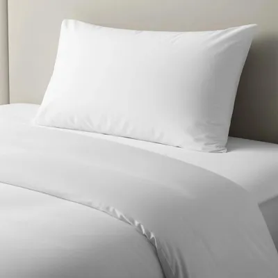 A white pillow and duvet cover are neatly arranged on a bed.