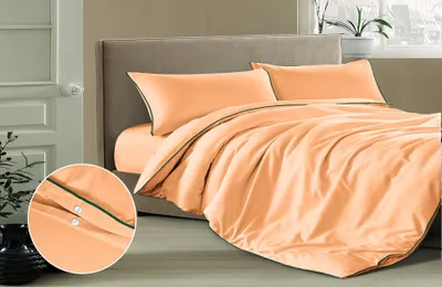 A neatly made bed with apricot-colored bedding and pillows.