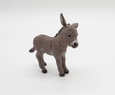 A toy donkey foal is shown standing on a white background.