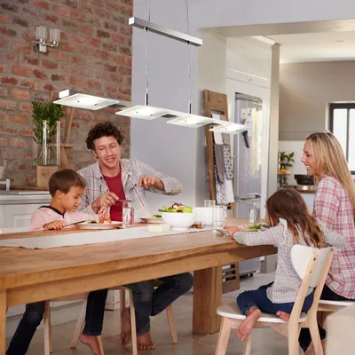 A family is having dinner at a wooden table in a modern kitchen.