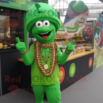 Obrázok produktu pre Zelená postava maskota REDBROKOLY, oblečená v overale a s náhrdelníkmi, predstavuje Tikka Masala