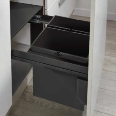 A close-up view of a pull-out waste bin system installed in a kitchen cabinet.