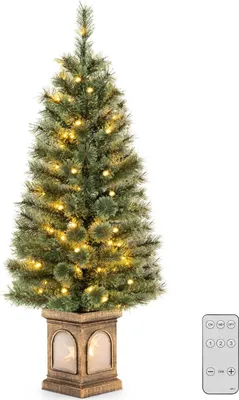 A decorated artificial Christmas tree in a pot with a remote control.