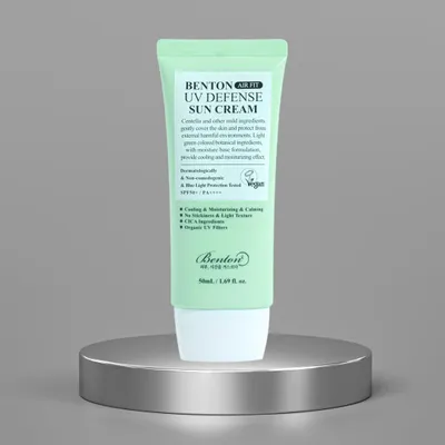 A green tube of sunscreen sits on a silver pedestal against a gray background.