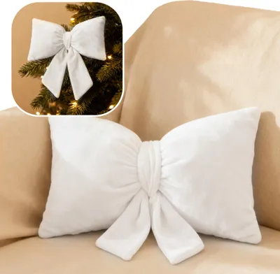 A white bow-shaped pillow is placed on a beige sofa. A small inset image shows a similar bow on a Christmas tree.