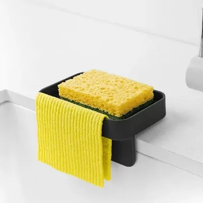 A kitchen sink sponge holder with a yellow sponge and a yellow dish towel hanging from it.