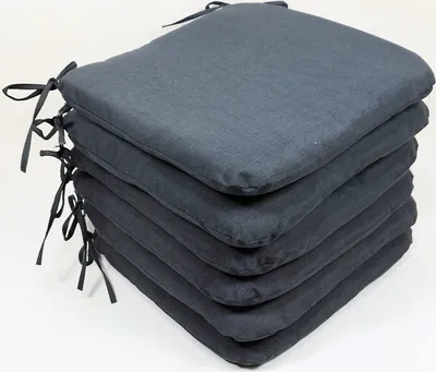 A stack of six dark grey seat cushions with ties.