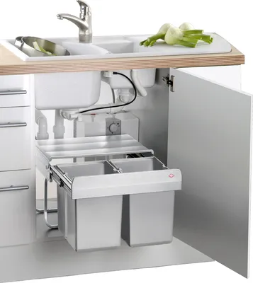 A kitchen sink area with a pull-out trash bin system underneath.
