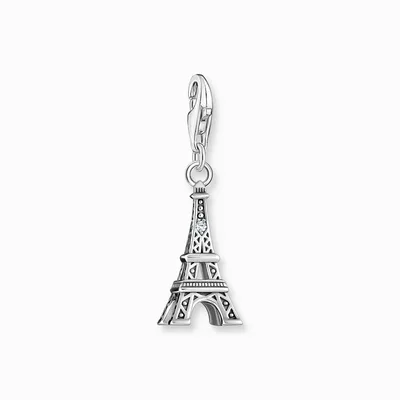A silver Eiffel Tower charm with a small blue gem, attached to a silver clasp, against a white background.