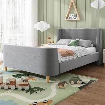 A child's bedroom with a gray upholstered bed, toys on the floor, and cloud-shaped decorations.
