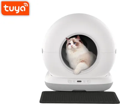 A white, spherical automatic cat litter box with a cat inside, placed on a black mat.