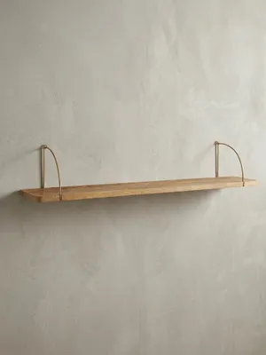 Freigestelltes Wandregal 120x25x22 cm in Frontalansicht, das die klaren Linien des massiven Mangoholzes und der beiden goldfarbenen Metallhalterungen hervorhebt._#sku_BARWL6.598#