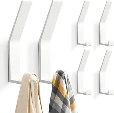 A set of six white wall-mounted coat hooks, with two hooks in the foreground holding clothing items.