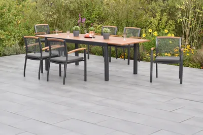 An outdoor patio set with a table and chairs, surrounded by greenery and flowers.