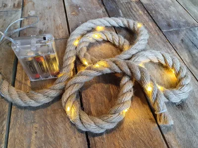 A coiled rope light with a battery pack on a wooden surface.