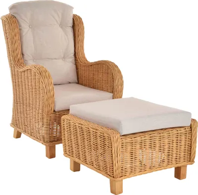 A wicker armchair with a matching ottoman, both with beige cushions, presented against a white background.