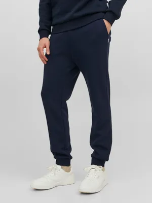 A man wearing navy sweatpants and white sneakers.