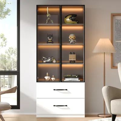 A modern display cabinet with glass doors and drawers, showcasing various decorative items and books. The cabinet is illuminated with LED lights and is placed in a well-lit room with a window and a floor lamp.