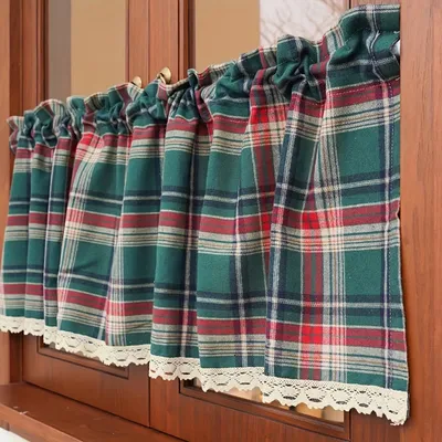 A close-up view of plaid kitchen curtains hanging in a wooden window frame.