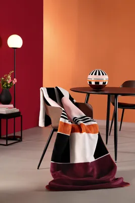 A blanket draped over a chair in a room with red and orange walls.