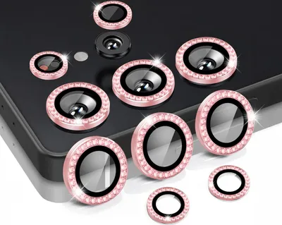 A collection of camera lens protectors with decorative rhinestones arranged on a dark surface.