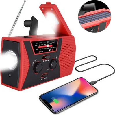 A red and black emergency radio is shown charging a smartphone.