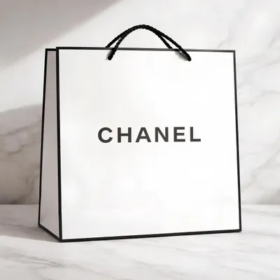 Immagine prodotto di Borsa regalo bianca con la scritta “Chanel”, il logo nero e la scritta “premium”