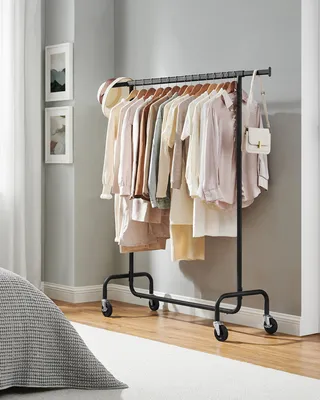 A clothing rack filled with pastel-colored women's clothing stands in a well-lit room.